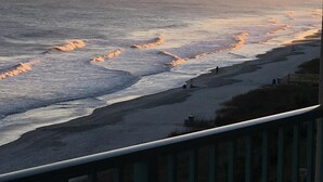 Une vue sur la côte, avec des vagues, une plage de sable et une clôture en bois.