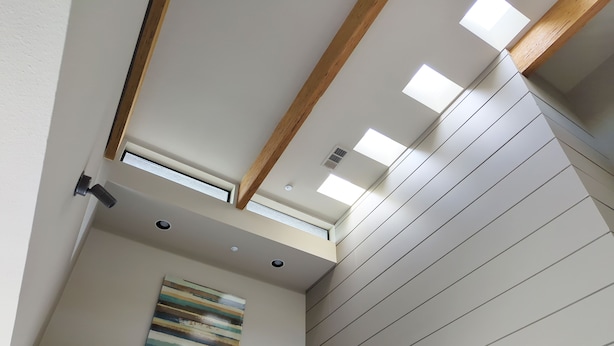 A modern interior with a sloped ceiling, skylights, recessed lighting, and a single piece of abstract art. - Palm Springs - Central & Modern! (Palm Springs)
