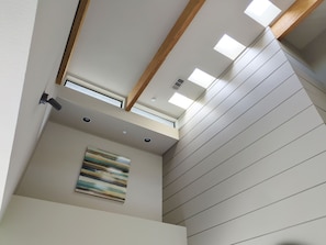 A modern interior with a sloped ceiling, skylights, recessed lighting, and a single piece of abstract art. - Palm Springs - Central & Modern! (Palm Springs)