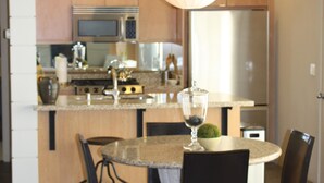 A modern kitchen with wooden cabinets, a central island, and a dining area with chairs. - Palm Springs - Central & Modern! (Palm Springs)