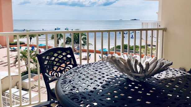 Un balcon avec vue sur la mer, comprenant une table ronde et des chaises, ainsi qu’une balustrade.
