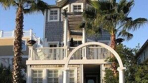 Uma casa de dois andares com varanda, um alpendre com guarda-corpo branco e entrada com portão.