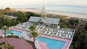 Um resort com área de piscina, espreguiçadeiras e vista para a praia.