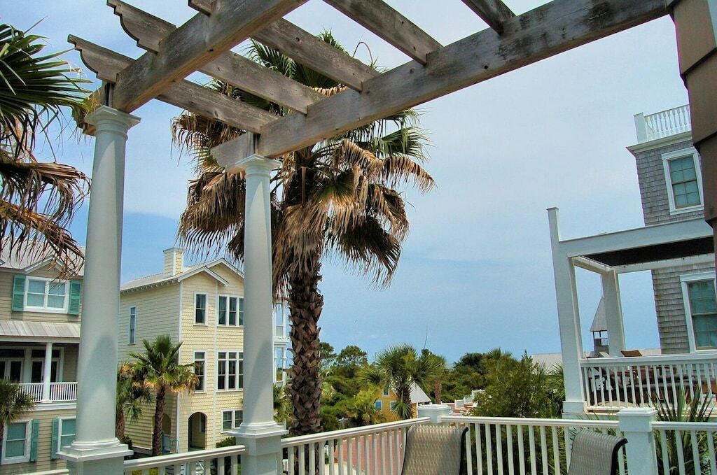 A coastal building with a balcony, palm trees, and a clear view of the ocean.