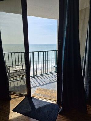 A balcony with a view of the beach and ocean.