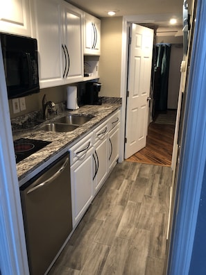 Kitchen features white cabinetry, stainless steel sink, microwave, and dishwasher.