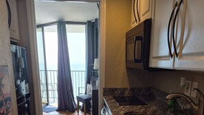 A modern kitchen with granite countertops, stainless steel appliances, and a view to a balcony.