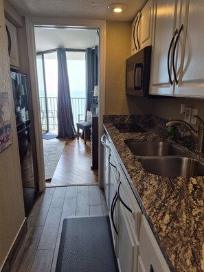 A modern kitchen with granite countertops, stainless steel appliances, and a view to a balcony.