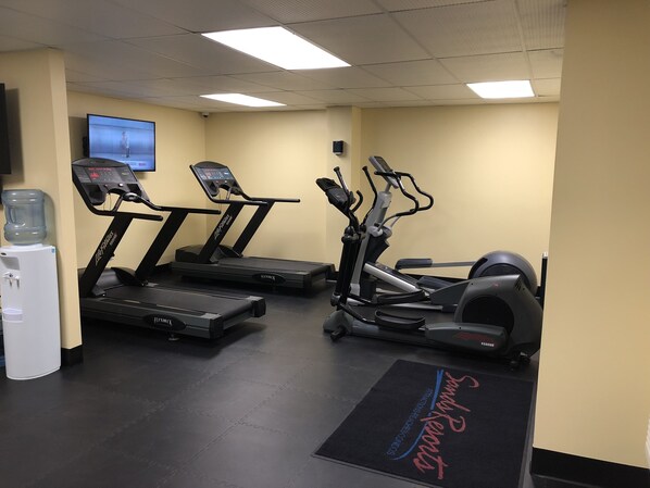 A gym with treadmills, an elliptical, and a water dispenser.