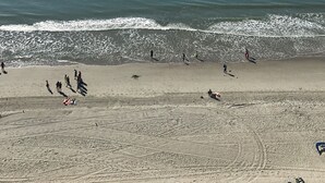 A beach with people walking along the shore and a clear view of the ocean.