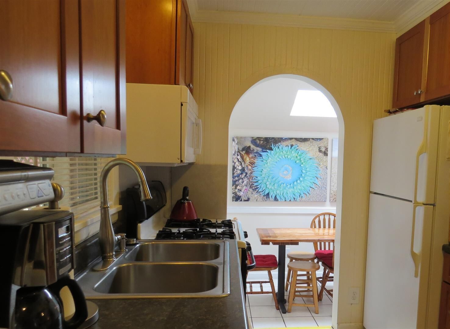 A kitchen with wooden cabinets, a gas stove, a sink, and a refrigerator.