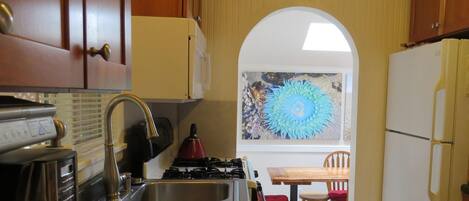 A kitchen with wooden cabinets, a gas stove, a sink, and a refrigerator.