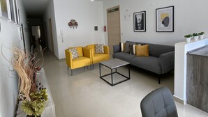 Ein modernes Wohnzimmer mit einer Couch, zwei Sesseln, einem Couchtisch und einem Essbereich.