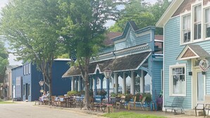 A street with a blue building featuring a porch with outdoor seating.