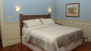 A bedroom with a wooden bed, white bedding, and two wall-mounted lights. - Renovated Train Station on Thoroughbred Horse Farm (Paris)
