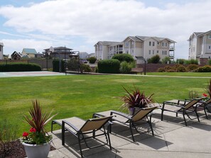A residential area with a well-maintained lawn, outdoor seating area with chairs, and a basketball court. - Beach View Condo in Westport - perfect vacation get-away (Westport)