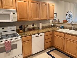 A kitchen with wooden cabinets, a microwave, stove, and a sink. - Beach View Condo in Westport - perfect vacation get-away (Westport)
