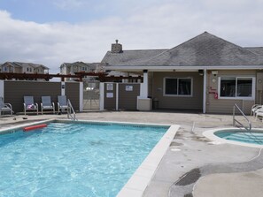 A swimming pool area with a lifeguard station, lounge chairs, and a covered seating area.