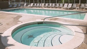 A circular hot tub with a starfish decoration, surrounded by lounge chairs and a pool in the background.
