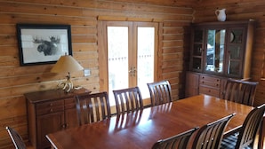 A wooden dining room with a large table and chairs, a cabinet, and a lamp. -  Log Home in the NATIONAL FOREST.  ATV/SNOWMOBILE TRAIL CROSS OUR PROPERTY (Hayward)