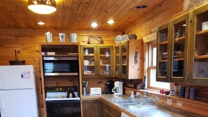 A wooden interior with a kitchen area featuring a refrigerator, oven, microwave, and sink. -  Log Home in the NATIONAL FOREST.  ATV/SNOWMOBILE TRAIL CROSS OUR PROPERTY (Hayward)