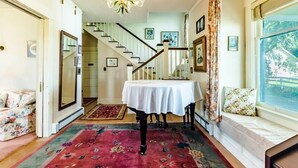 Ein Zimmer mit Treppe, einem Tisch mit weißem Tischtuch und einem Fenster mit Blick.