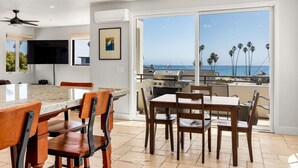 A modern kitchen with a large island, dining area, and a balcony with a view of the ocean. - Luxurious Sea Crest Oceanview Villa- by Main Beach (Santa Cruz)