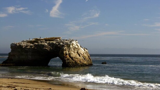 A coastal rock formation with an arch, a sandy beach, and the ocean. - Luxurious Sea Crest Oceanview Villa- by Main Beach (Santa Cruz)