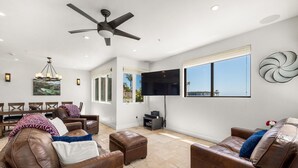 A spacious living room with leather sofas, a ceiling fan, a flat-screen TV, and a dining area with a table and chairs. - Luxurious Sea Crest Oceanview Villa- by Main Beach (Santa Cruz)
