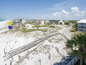 Une zone côtière avec une plage de sable, une promenade en bois et des bâtiments en arrière-plan.