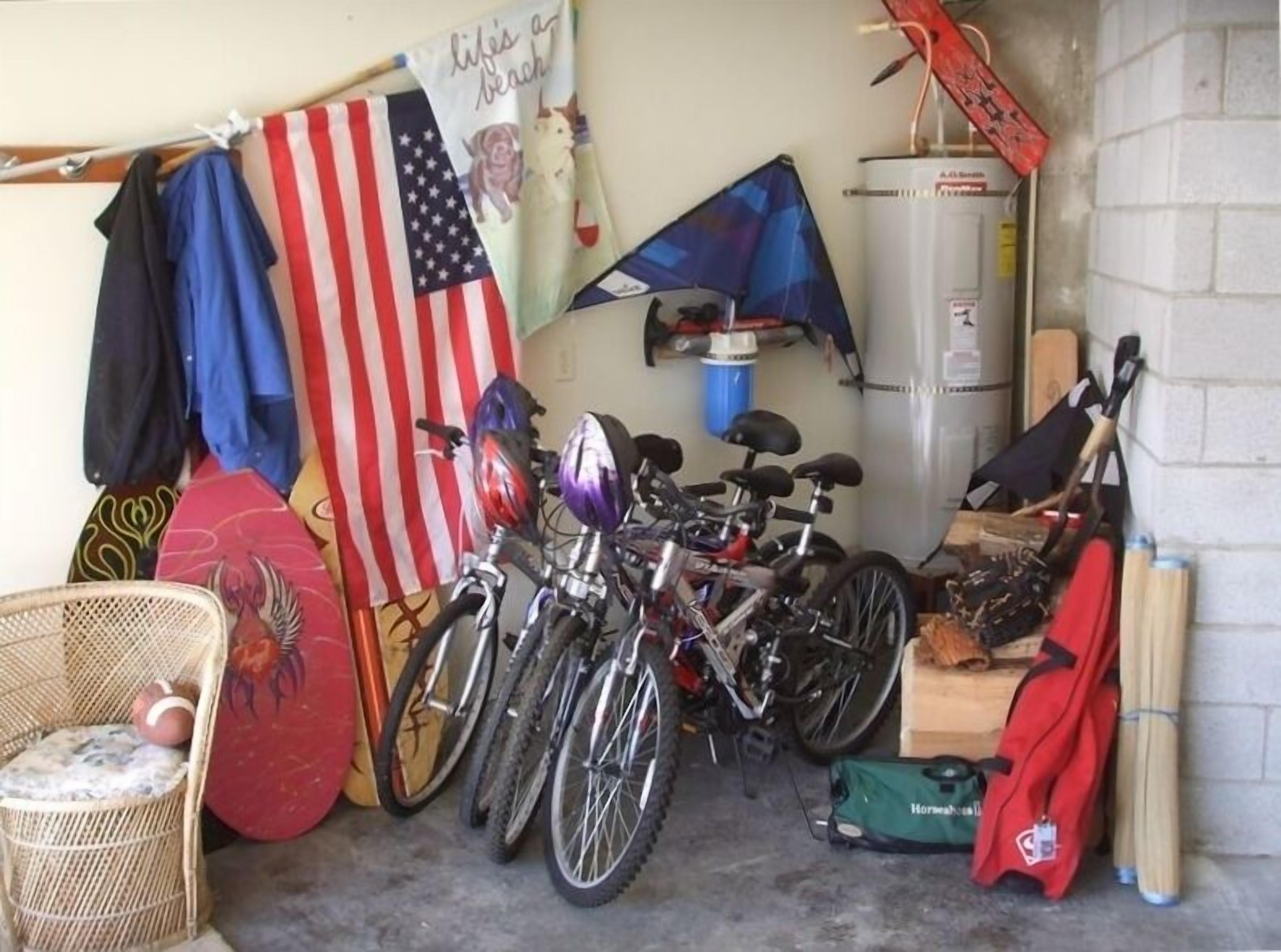A garage with bicycles, a water heater, and various items on shelves.