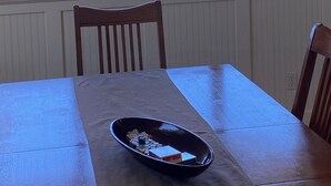A dining table with a bowl of snacks, a chair, and a view of the ocean through large windows. - Beach Star - Classic, Elegant & Comfortable Beachfront Home! (Rockaway Beach)