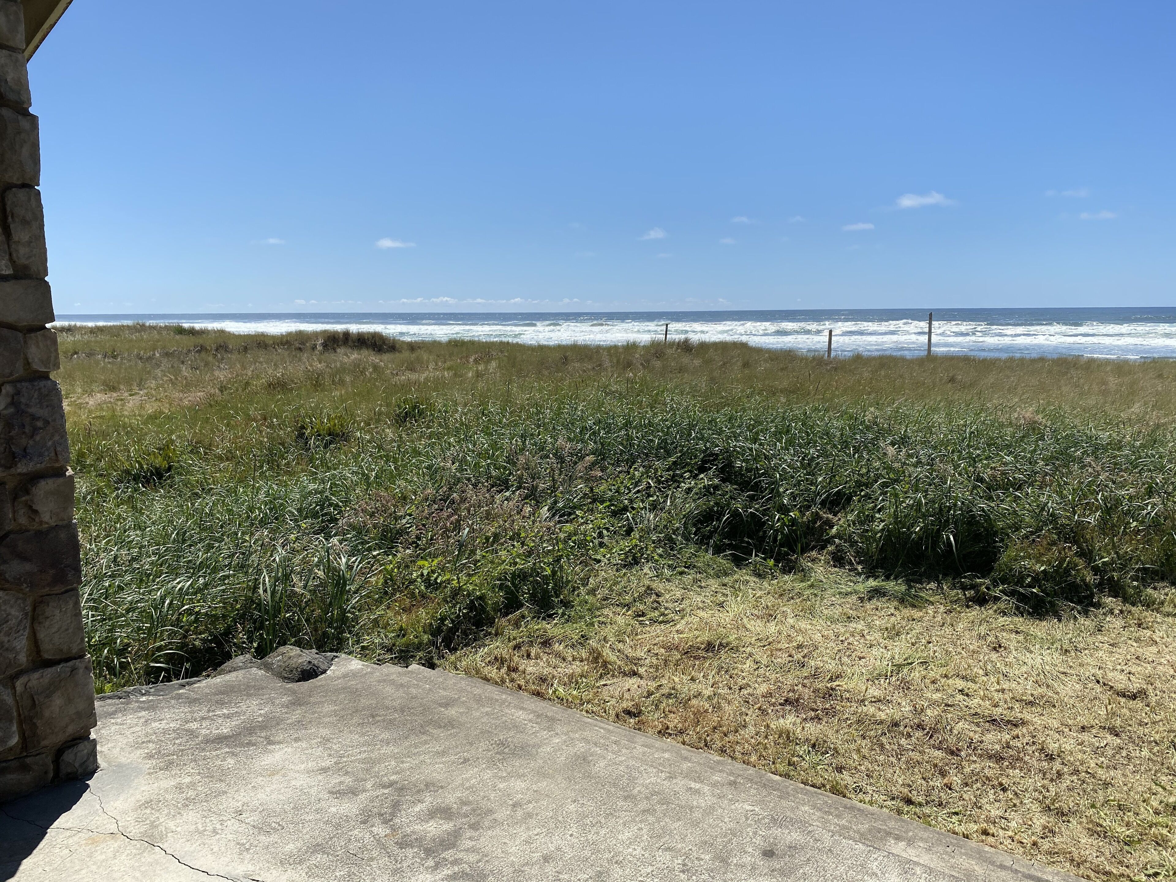 Une vue sur la côte, avec un mur de pierre et un chemin en béton menant à la plage.