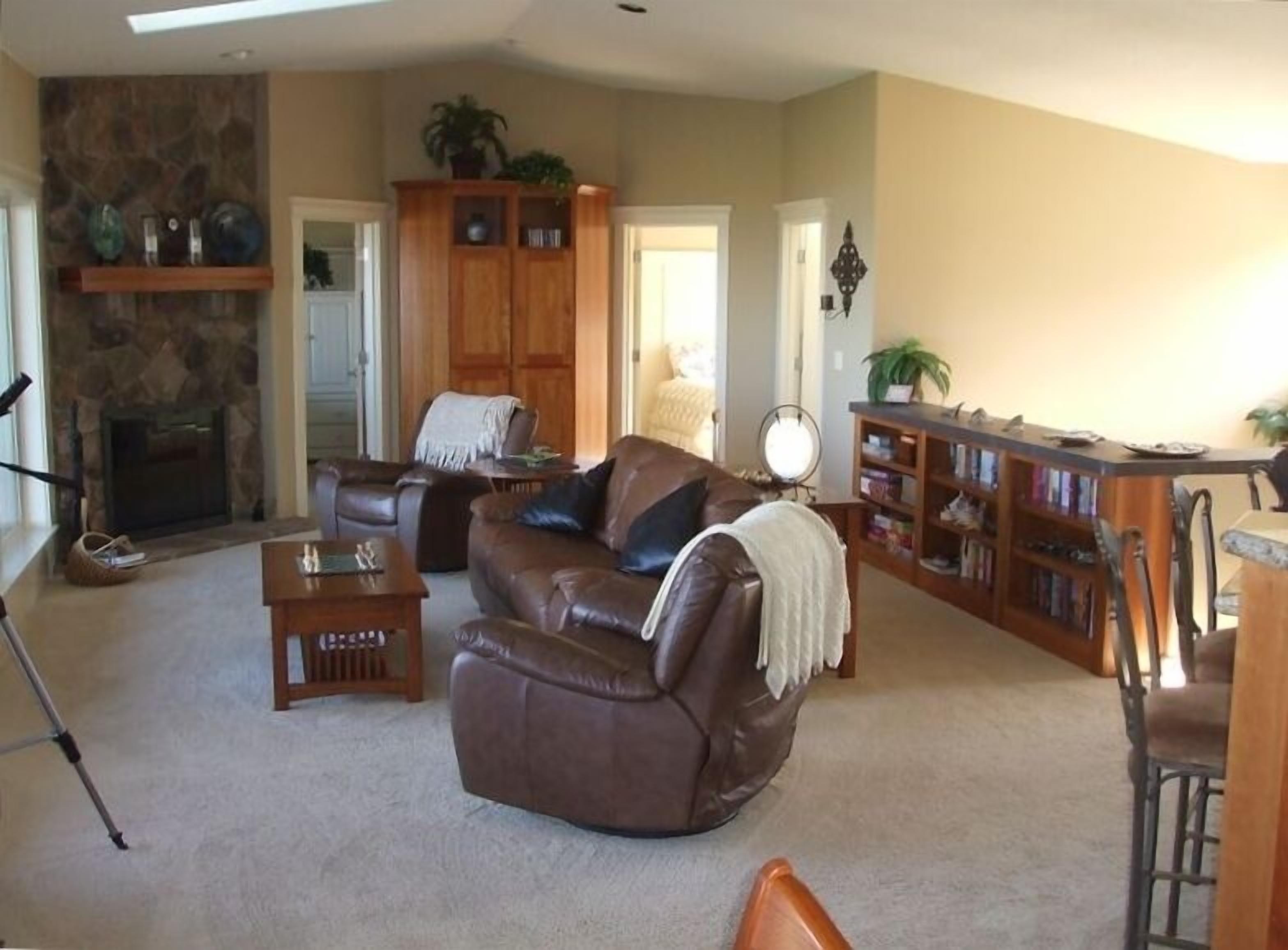 A living room with a fireplace, leather sofa, and a bookshelf.