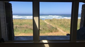 A room with a large window overlooking a grassy path and the ocean. - Beach Star - Classic, Elegant & Comfortable Beachfront Home! (Rockaway Beach)
