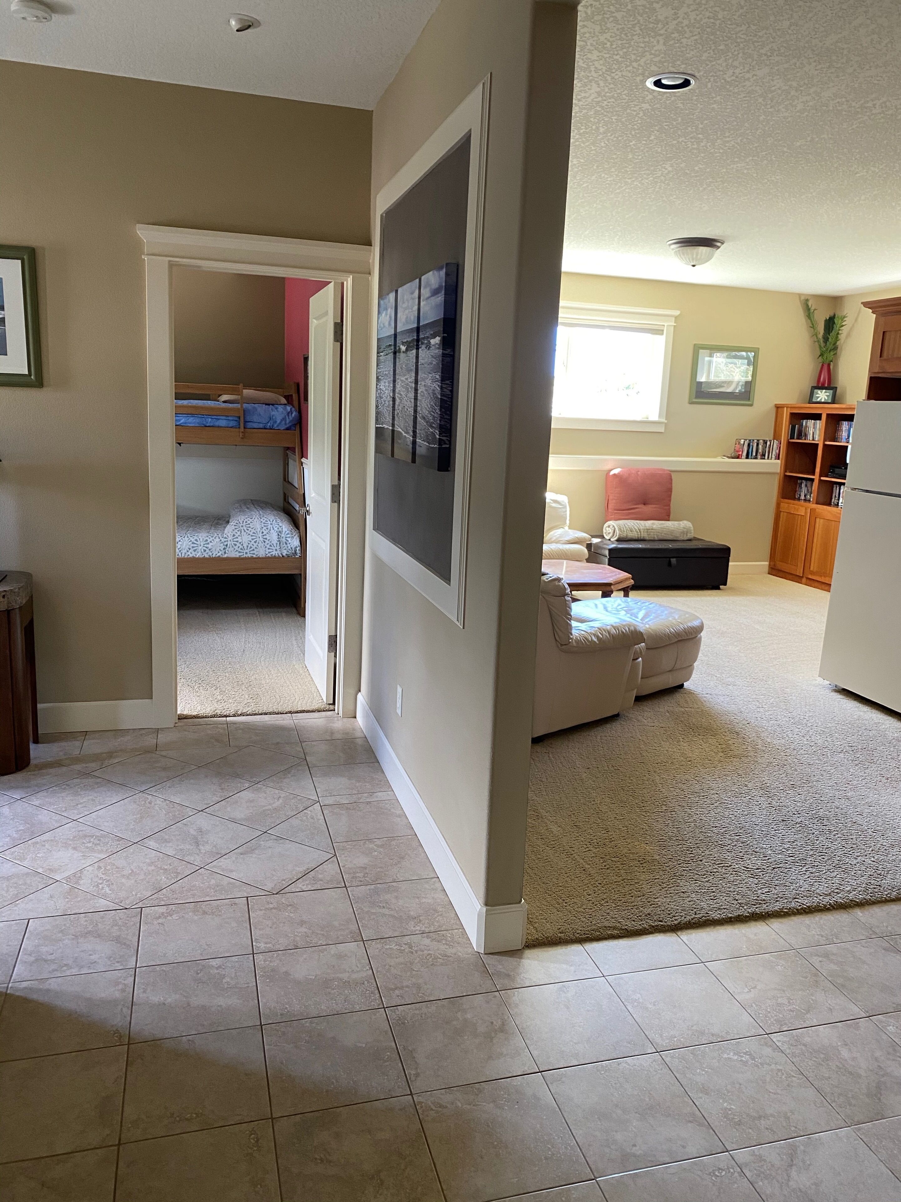 A spacious living room with a large window, a cozy seating area, and a kitchen area.