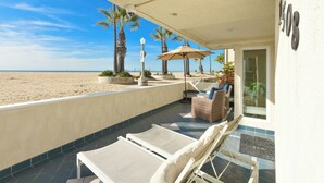 Un balcón con sillones de descanso, una mesa y una sombrilla con vista a la playa.