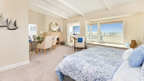 Ein Schlafzimmer mit einem großen Bett, einem Schreibtisch und Blick auf den Strand.