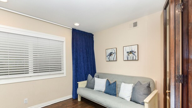 Una sala de estar con un sofá gris, cortinas azules y dos obras de arte en la pared.