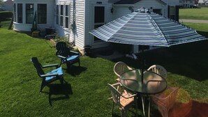A large white house with a covered patio area featuring outdoor furniture.