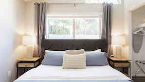 A bedroom with a large bed, two bedside tables with lamps, a window with curtains, and a wall-mounted rack with a towel. - The "Pool Cottage" Upgraded Home FREE Heated Pool (Phoenix)
