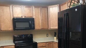 A kitchen with wooden cabinets, a black microwave, a black stove, and a black refrigerator. - Great location!! Pool! Unit 5201- Mtn. View Condos, 3 Bed, 2 Bath (Pigeon Forge)