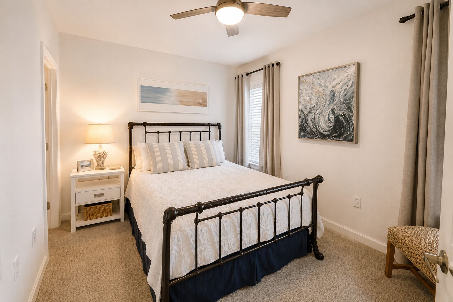 A bedroom with a bed, nightstand, lamp, and artwork.