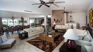 A spacious living room with a large coffee table, sofas, and a ceiling fan.