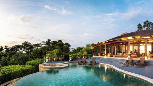 A poolside area with a wooden deck, lounge chairs, and a covered seating area with tables and chairs. - Welcome to Casa Caiman | FULL STAFFED + 2 BOATS by Viridian Experience (peninsula papagayo)