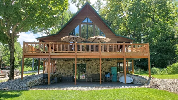 Une cabane en bois dotée d’un balcon, de murs en pierre et d’un espace salon extérieur.