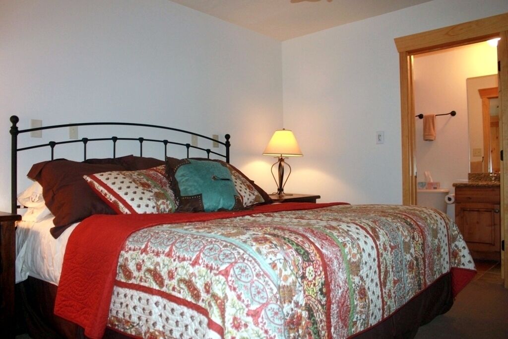 Un dormitorio con una cama, una lámpara de noche y un armario de madera.