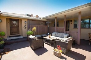 Un patio cubierto con mobiliario exterior, una puerta y una pequeña zona de porche.