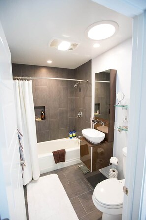 Un baño moderno con bañera, inodoro y zona de ducha.