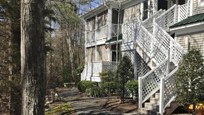 Ein zweistöckiges Haus mit weißer Fassade, einer Veranda und einer Holztreppe.